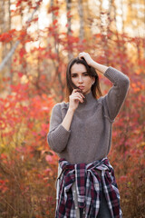 Beautiful girl posing in autumn forest under sunlight