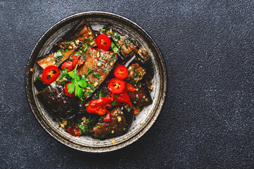 Grilled eggplant with hot red peppers, soy sauce and garlic in asian style, black background, top view