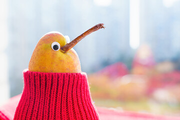 Pear character wearing ed sweater sits by a window