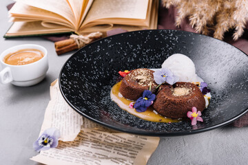 Chocolate lava cake with ice cream served on plate against cup of coffee