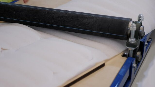 Close-up of a special machine for rolling sintepon in the atelier for the production of bags.