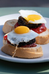 Typical spanish tapas with fried egg, chorizo and fried pepper.