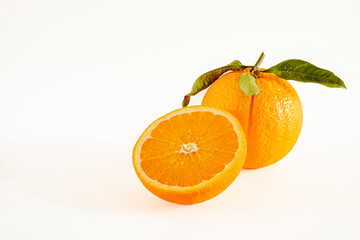 Orange with cut in half and green leaves isolated on white background.