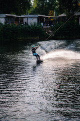 Naklejka premium A guy in a yak suit at sunset jumps from a springboard on a wakeboard in an extreme park in Kiev. Ukraine.