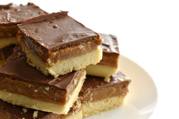 Millionaire's shortbread with chocolate and caramel on a parchment paper with copy space on the right side.	
