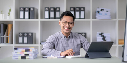 Young handsome asian Ceo manager businessman middle-aged man around the age of 35 sitting in office near windows holding hands looking at camera and smile. - obrazy, fototapety, plakaty