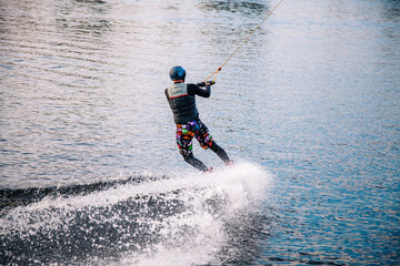 A guy in a yak suit at sunset jumps from a springboard on a wakeboard in an extreme park in Kiev. Ukraine.