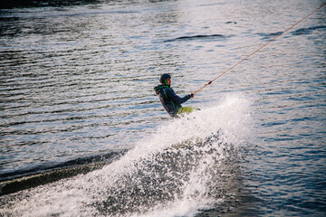 A guy in a yak suit at sunset jumps from a springboard on a wakeboard in an extreme park in Kiev. Ukraine.