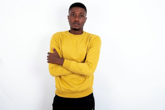 Picture of angry young handsome man wearing yellow sweater over white background looking camera.