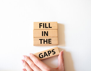 Fill in the gaps symbol. Concept words fill in the gaps on wooden blocks. Beautiful white background. Businessman hand. Business and fill in the gaps concept. Copy space.