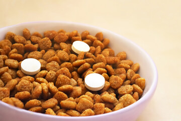 Cat food with three pills in a bowl on the floor. Vitamins for cats. Cat treatment