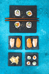 Variation of nigiri and maki shushi on slate plates on blue background, top view