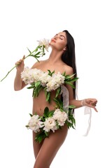 Sensual young woman with flowers on naked body touching face in studio