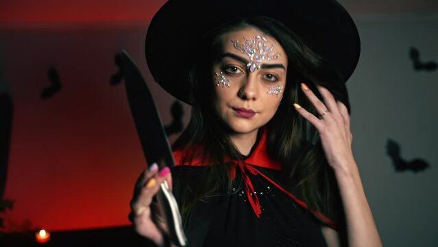 A girl dressed as a witch is dangerously holding a knife in her hands