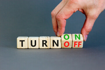 Turn on or off symbol. Concept words Turn off and Turn on on wooden cubes. Beautiful grey table grey background. Businessman hand. Business Turn on or off concept. Copy space.