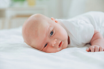 Cute 2-month-old baby lying on the bed, natural bed linen. delicate baby skin.