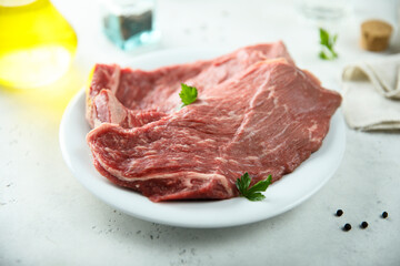 Raw beef steak on a white plate