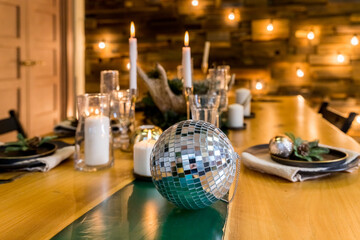 mirror ball, white candles and Christmas decor on wooden table.kitchen is decorated in a Christmas style with white accents. Cozy atmosphere of winter holidays.New Year holiday concept.