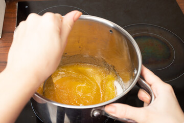 Cooking Christmas dessert ginger cookies, gingerbread, Women's hands add warm honey on the stove in the kitchen