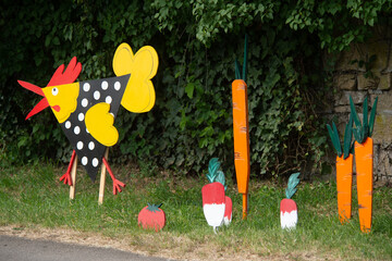 décoration extérieures dans un petit village avec une poule, des légumes, radis, carottes, découpés dans des planches en bois et peints avec des couleurs vives