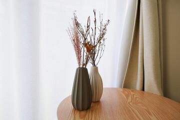 White and gray vase on a natural brown wooden table with white dried flowers in a room. autumn and winter interior image photo. 