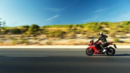 Obraz na płótnie Canvas Side view of a motorcycle rider riding red race motorcycle on the highway with motion blur.