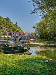 Fototapeta na wymiar Rijeka Crnojevica, a picturesque small fishing village and tourist destination with an arched limestone bridge. It is famous for the boat trips. Montenegro, Europe