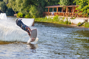 The wakeboarder makes a sharp turn over the surface of the water at high speed, creating a heap of spray behind him.