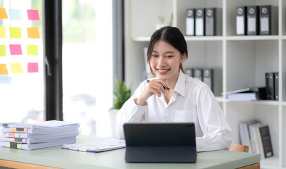 Asian Businesswoman Using laptop computer and working at office with calculator document on desk, doing planning analyzing the financial report, business plan investment, finance analysis concept.