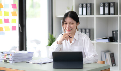 Obraz premium Asian Businesswoman Using laptop computer and working at office with calculator document on desk, doing planning analyzing the financial report, business plan investment, finance analysis concept.