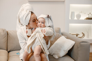 Charming mother and little baby daughter with hair wrapped in towels