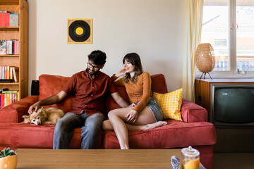 couple at home in living room with dog on sofa