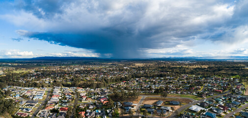 rain falling from distant clouds in sky looking over residential area of town