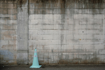 Old gray brick wall and traffic cone in street