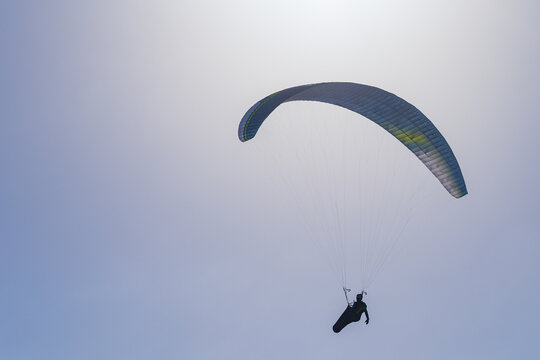 A parasailer silhouetted high in a sunny blue sky