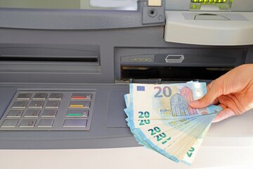 hand who withdraws money in european twenty euro banknotes in the atm automatic teller machine