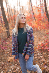 Young beautiful woman in knitted cardigan walking in the autumn forest.