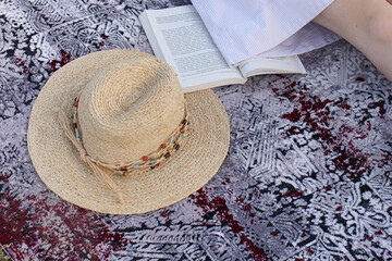 a straw hat on the carpet and a book next to it