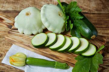 The raw product zucchini zucchini and patissons are on the wooden surface of the table. Ingredients for cooking. Seasonal vegetables.