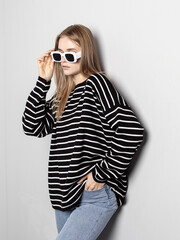 Woman in black cotton casual oversize sweatshirt and sunglasses on gray background. Clothes for walking