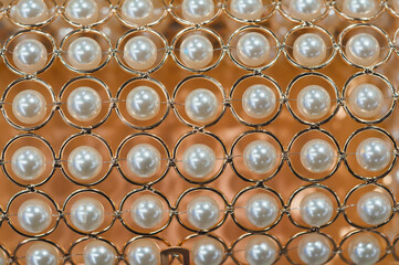 Decorative ornament of pearls in a gilded openwork lattice. Background with soft focus