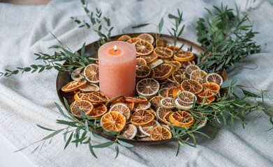 Adventsschale mit Kerze, Eukalyptus und getrockneten Orangenscheiben auf goldenem Teller dekoriert...