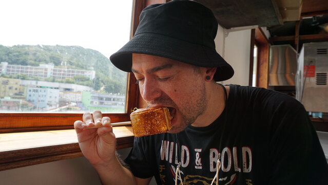 Hombre de mediana edad con sombrero negro comiendo un helado recubierto con malvavisco tostado