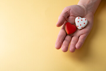 Fototapeta na wymiar Small heart shape cookies love concept in hand copy space golden background