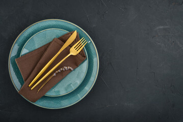 table place setting with blue plates and golden cutlery on black  background