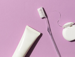 Dental care concept frame with toothbrush, tooth floss and toothpaste on the bright violet...