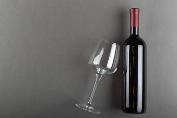 Corked bottle of red wine and empty wine glass on gray background. Alcoholic drink. Winemaking...