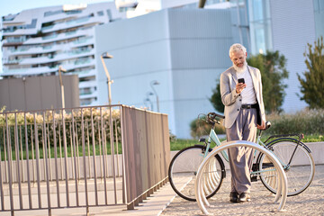 Old senior business man holding smartphone using bike rental digital phone mobile app to rent...