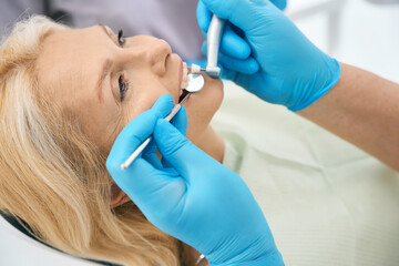 Fototapeta premium Beautiful woman patient is receiving dental checkup in medicine center