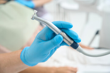 Dentist is holding metal equipments in arm in medicine clinic